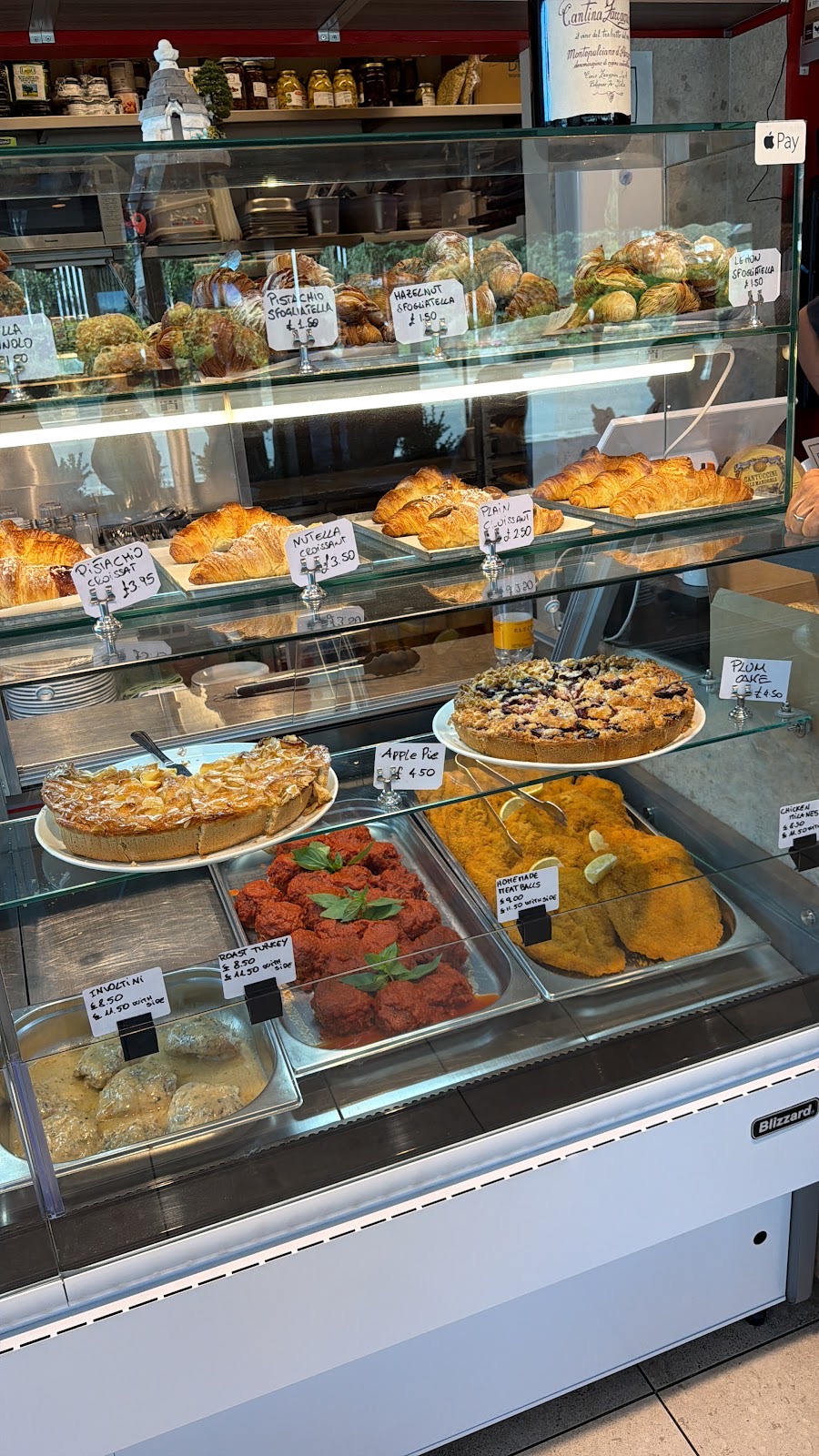 Deli counter stacked with quiches and trays of prepared antipasti