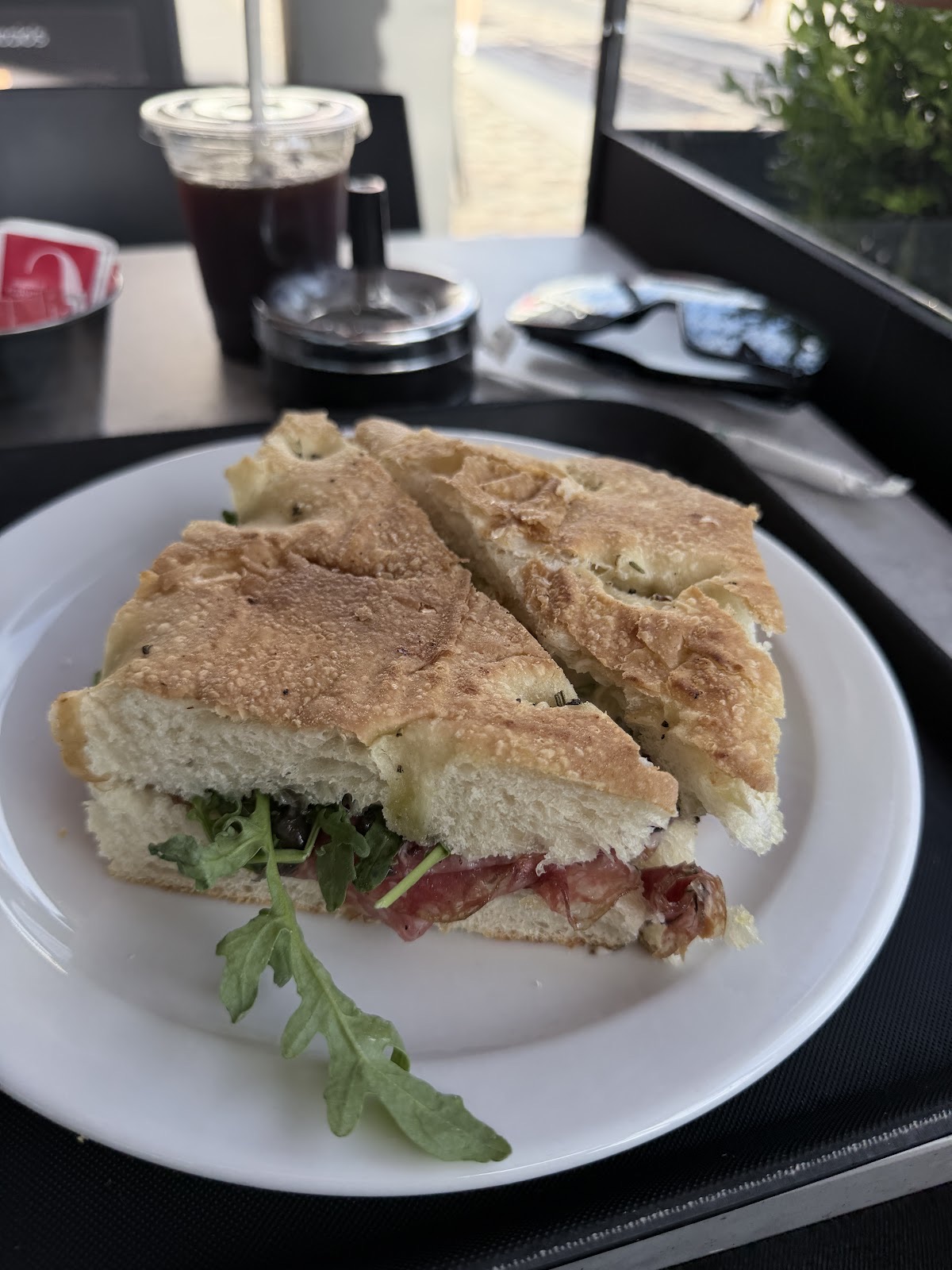 Focaccia sandwich cut in half on a white plate at the window bar
