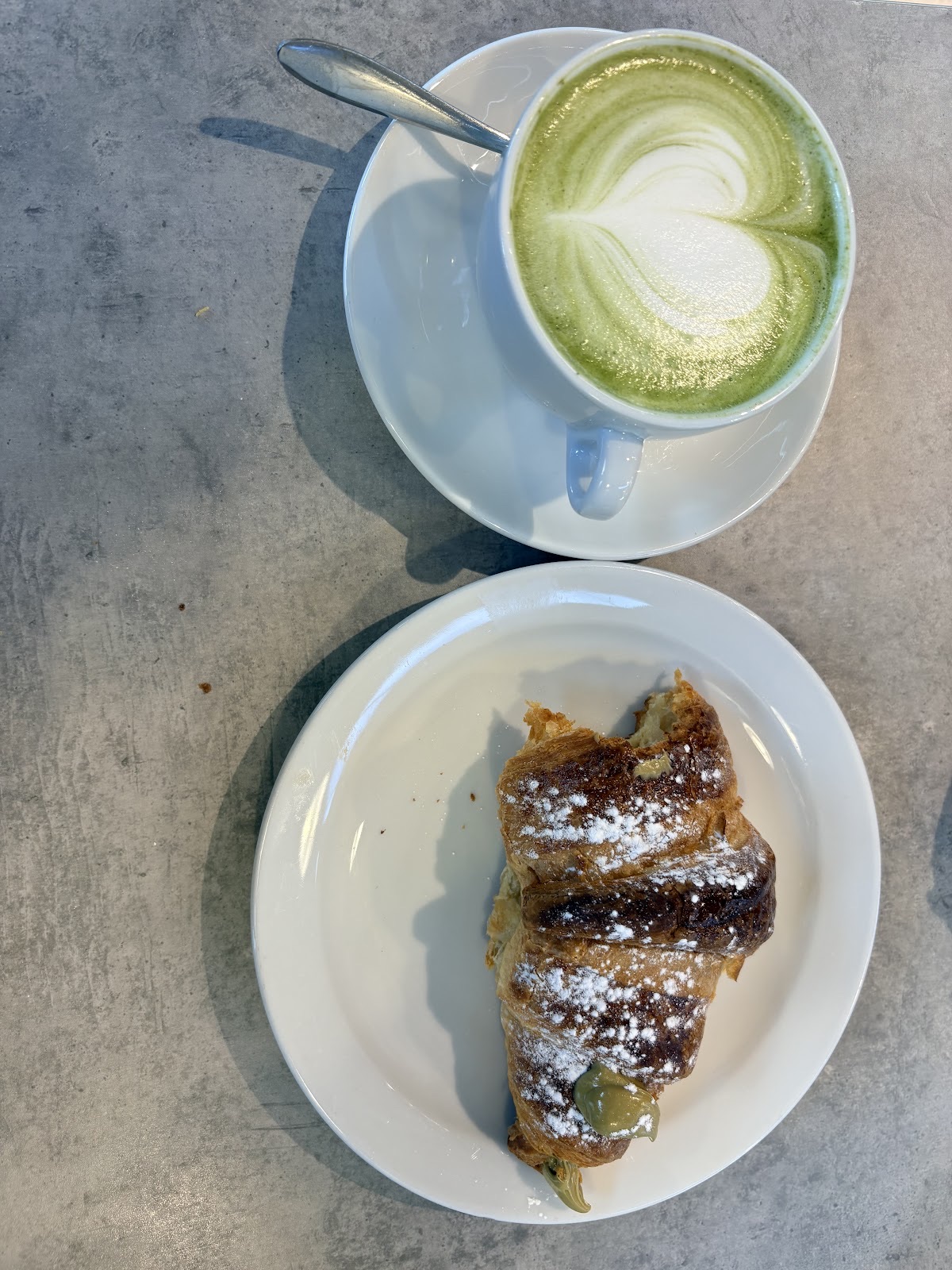 Pistachio-cream croissant beside a matcha latte